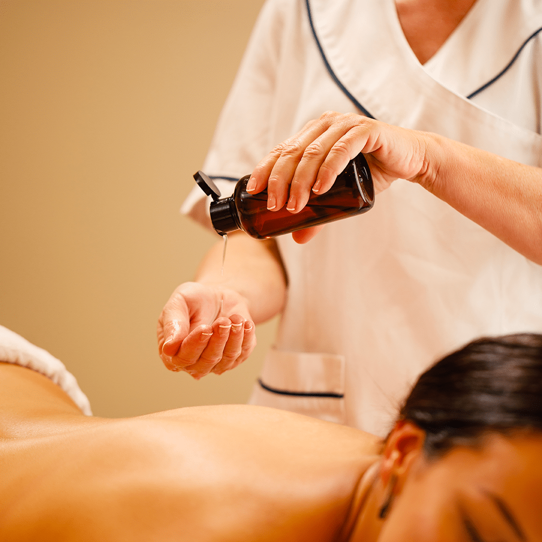 unrecognizable-therapist-pouring-oil-her-hands-before-massage-treatment-wellness-center